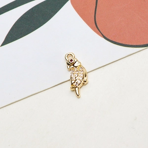 Macro shot of gold-plated parrot pendant with white cubic zirconia and red gem eye