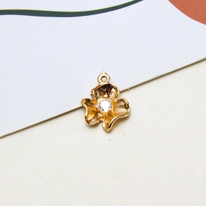 Macro detail of golden flower pendant with matte texture and sparkling center zircon