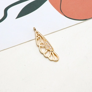 Macro detail of gold-plated wing pendant with white zircon inlay and hollow design
