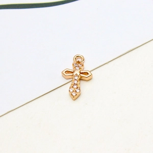 Macro view of gold plated cross pendant with shimmering white zircon inlay for DIY jewelry