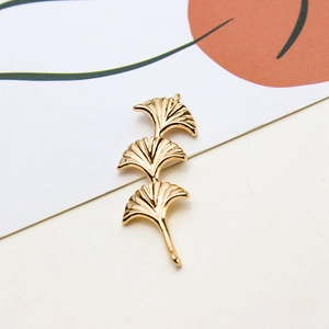 Makro-Detail von drei geschichteten goldenen Ginkgoblatt-Anhängern mit feiner Textur