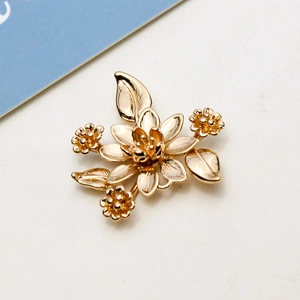 Macro shot of gold-plated metal flower pendant with detailed petals and leaves