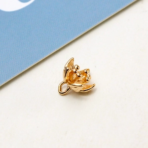 Detailed macro view of a golden vintage flower pendant with intricate petals and jump ring
