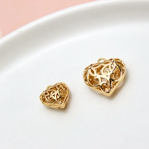 Detailaufnahme von zwei goldenen Herzanhängern mit Filigranmuster auf einer weißen Schale