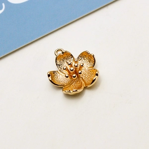 Macro view of gold-plated cherry blossom jewelry pendant with textured petals