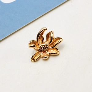 Detailed view of a golden lotus flower pendant with a fine brushed metal texture