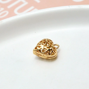 Detailansicht eines goldenen hohlen Herzanhängers mit filigranem Drahtdesign