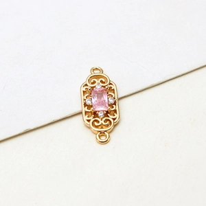 Close-up of gold-plated vintage hollow rectangular pendant with pink zircon stone