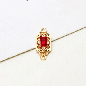 Detail of vintage gold plated pendant connector with red zircon and filigree pattern
