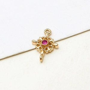 Macro view of gold-plated hollow floral pendant with pink stone and dual hanging loops