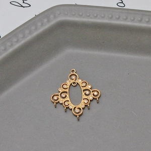 Macro detail of a baroque gold plated brass floral connector with five hanging loops