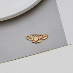 Détail d'un pendentif papillon doré vintage ajouré avec relief et boucles de connexion