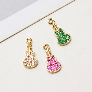 Detalle de colgantes con forma de guitarra bañados en oro con piedras de circón