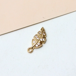 Macro view of gold-plated leaf pendant with sparkling zircon inlays and top loop