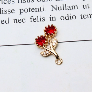 Macro shot of a gold flower charm with red stones and sparkling zircon leaf details