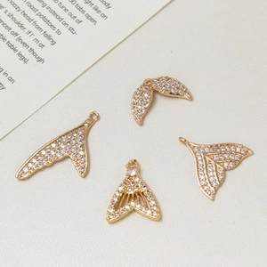 Detailed close-up of gold-plated mermaid tail charms with sparkling white zircons
