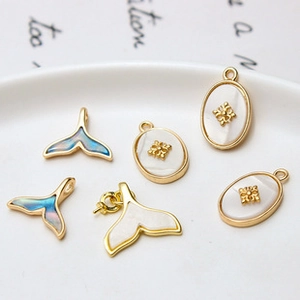Macro detail of gold-plated dolphin tail and oval charms with pearl inlay for DIY jewelry