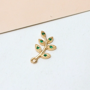 Macro detail of gold-plated leaf pendant with six sparkling green zircon stones