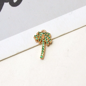 Detalle de colgante de cocotero bañado en oro con circonitas verdes para bisutería DIY