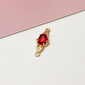Detail of gold-plated scrollwork connector with red oval zircon for DIY jewelry making