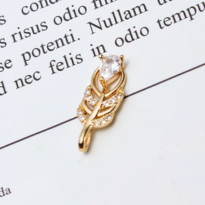 Macro detail of a golden feather pendant with shimmering pavé cubic zirconia inlay