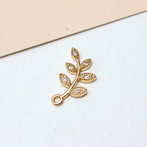 Macro shot of gold-plated leaf charm featuring five sparkling cubic zirconia crystals
