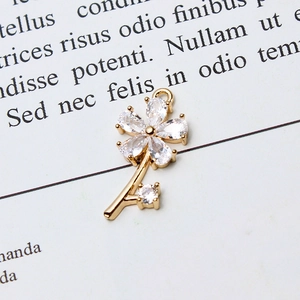 Macro shot of gold floral pendant featuring marquise-cut zircon petals on vintage paper