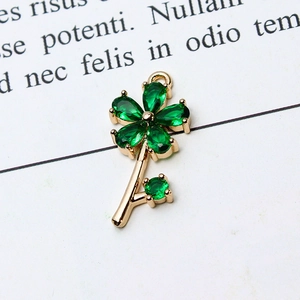 Macro shot of gold floral jewelry pendant with emerald green teardrop zircons on paper