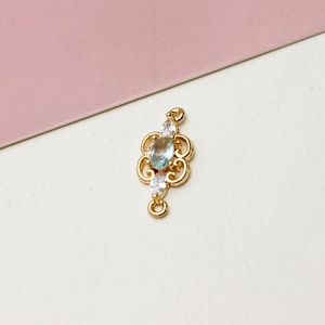 Macro view of gold-plated zircon connector with light blue oval stone and scrollwork