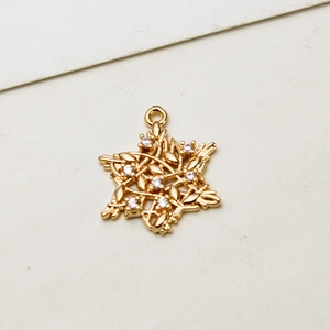Detail eines goldenen Hexagramm-Anhängers mit weißen Zirkon-Inlays und Blattmustertextur