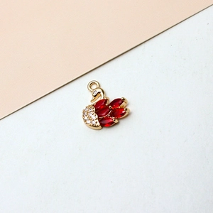 Macro shot of gold-plated swan pendant with red marquise gems and white zircon inlay
