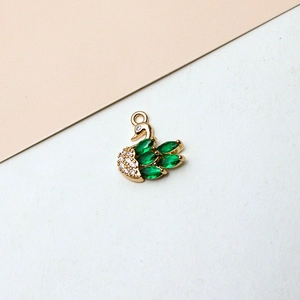 Detailed view of a gold-plated swan pendant with green zircon wings and clear crystals