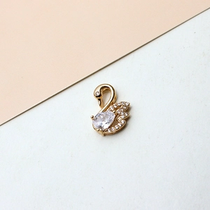 Detailed close-up of a gold-plated swan pendant inlaid with brilliant white cubic zirconia