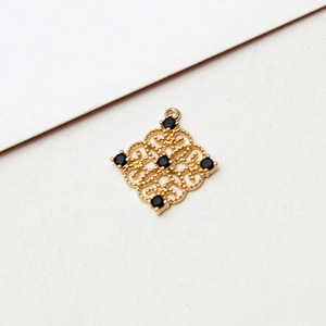 Macro view of gold plated hollow rhombus pendant with black gemstones for jewelry making