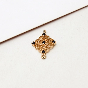 Macro shot of gold filigree square jewelry connector with five black gemstones