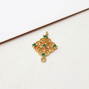 Macro shot of gold-plated hollow rhombus pendant with emerald green cubic zirconia stones