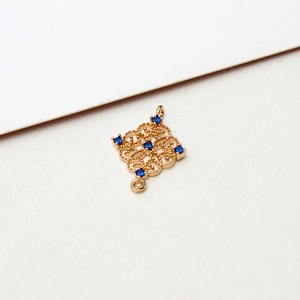 Macro shot of gold-plated hollow rhombus pendant with blue crystals for DIY jewelry