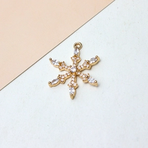 Vista macro de colgante de copo de nieve chapado en oro con circonitas para creación de joyas