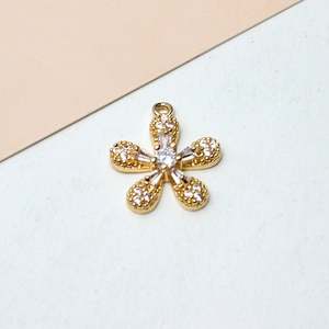 Detalle macro del colgante de flor de cinco pétalos bañado en oro con microcirconitas blancas