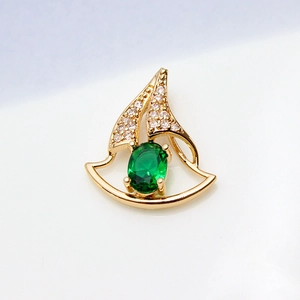 Macro view of gold-plated sailboat pendant with green gemstone and white zircon stones