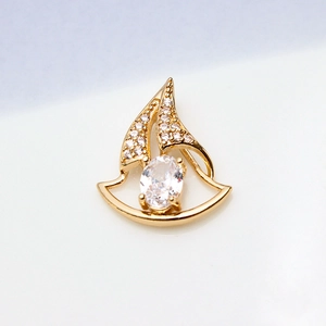 Macro shot of gold-plated sailboat pendant featuring clear zirconia stones on white background