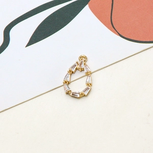 Macro detail of teardrop zircon pendant with baguette-cut stones and 18K gold plating
