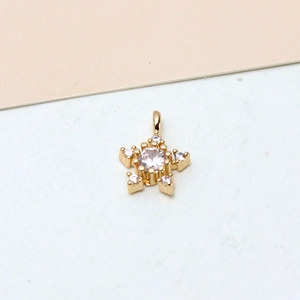 Macro detail of gold-plated snowflake pendant featuring zircon center and prong setting