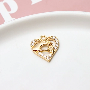 Macro shot of gold-plated heart pendant with zircon inlay showing two hands touching