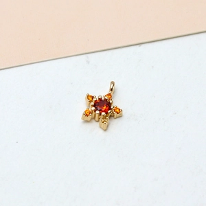 Macro detail of a 18K gold plated star pendant with orange zircon inlay for jewelry making