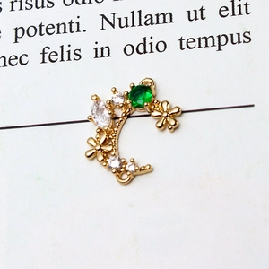Macro shot of gold plated floral pendant connector with green and white zircons