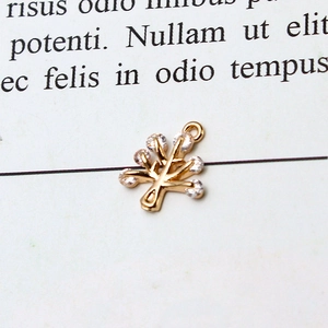 Detailed macro view of a golden tree-shaped pendant with cubic zirconia inlay for DIY jewelry