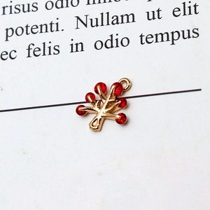 Detailed view of a gold tree pendant with red cubic zirconia on a minimalist paper background