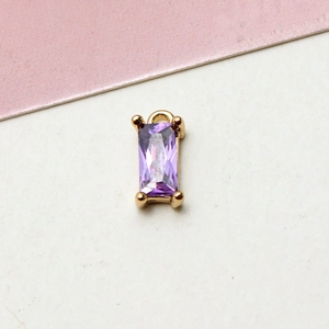 Macro shot of a rectangular purple zircon pendant with a gold-plated copper base