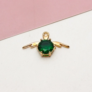 Detail of emerald green gemstone pendant with golden wings and four-prong setting
